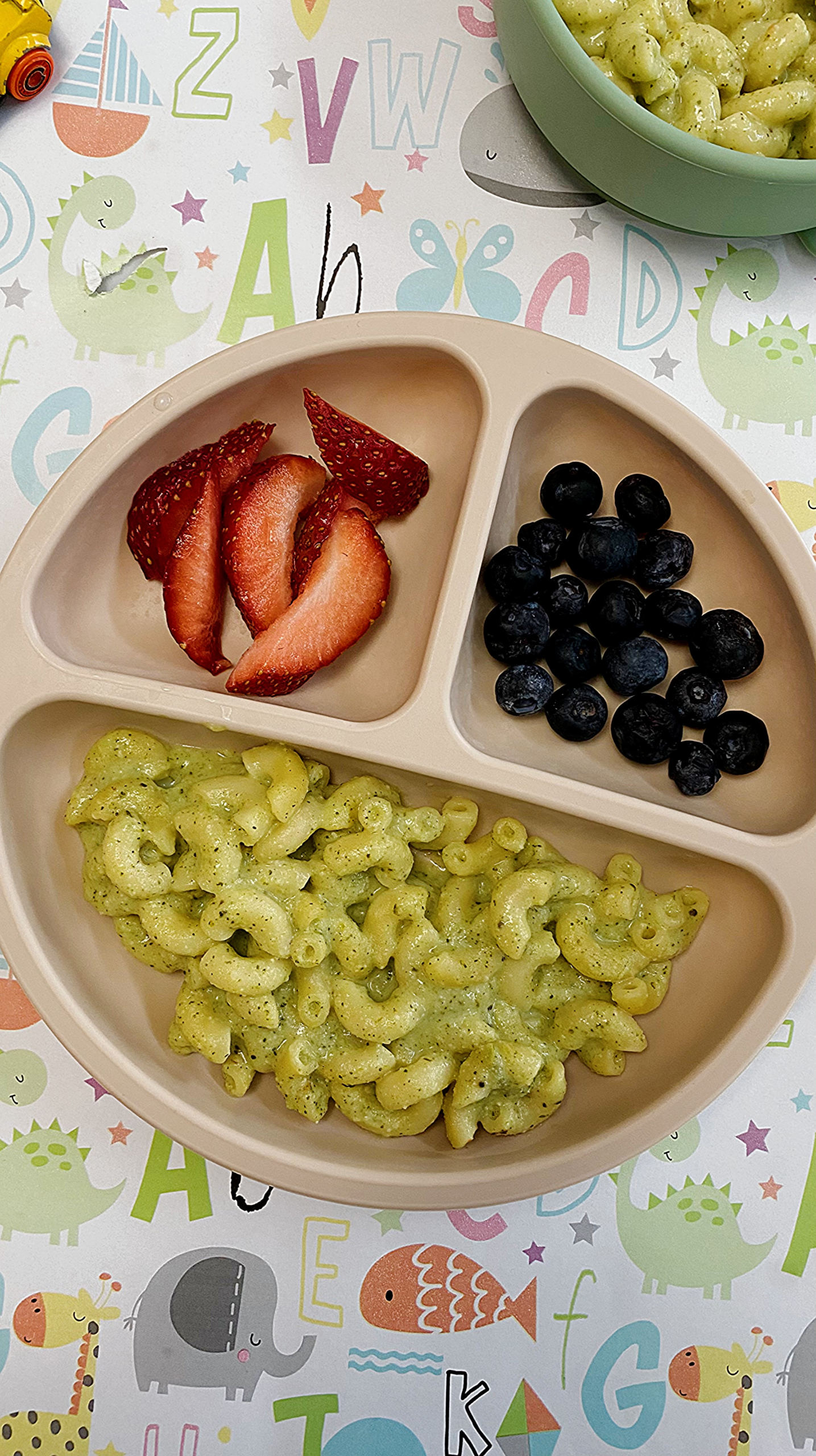 Plate of macaroni and cheese served with strawberries and blueberries on the side.