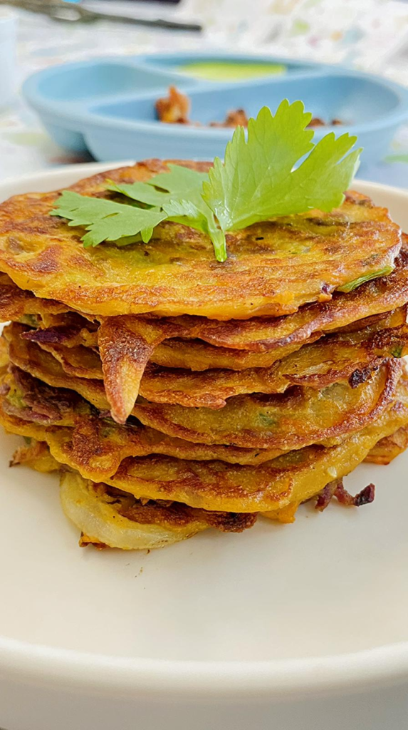 Stack of soft, savory veggie pancakes for toddlers, packed with hidden carrots, sweet potato, and eggs, served on a plate.